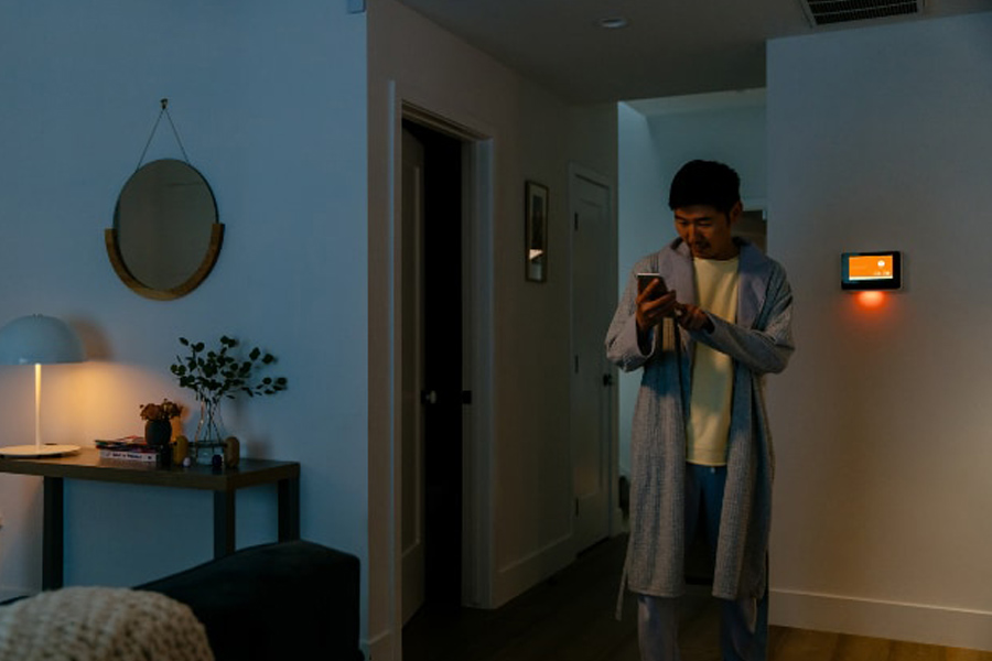 A man standing in his living room with his cell phone.