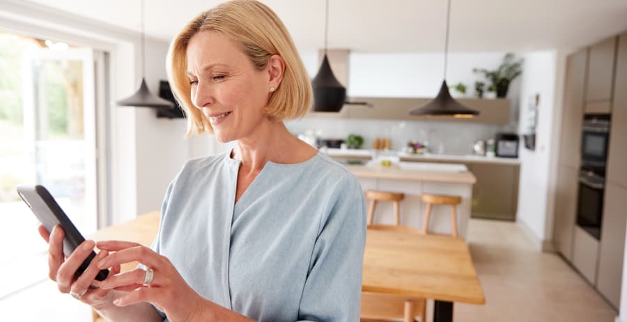 Woman holding a cell phone in a room filled with sunlight